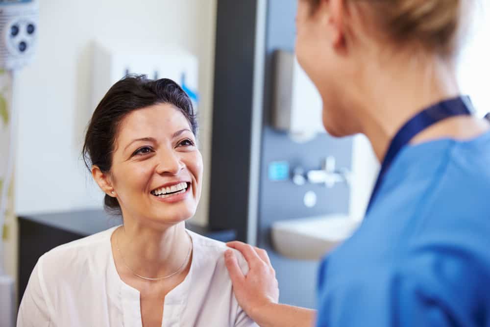 Female patient in hospital being reassured by healthcare worker